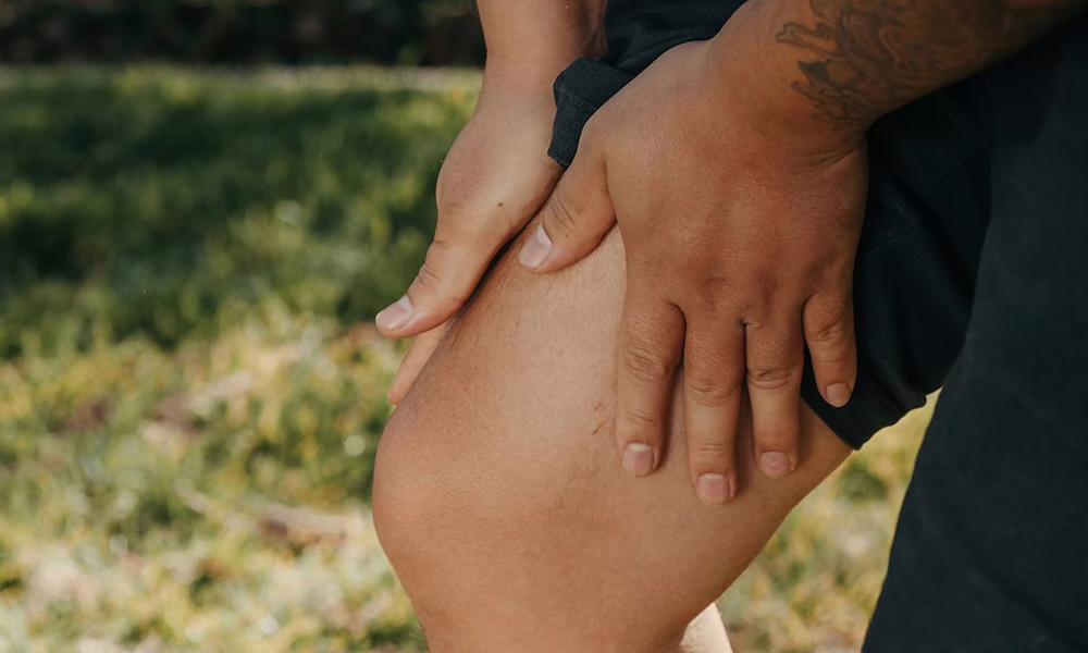 A person holding their leg, expressing discomfort while performing normal activities